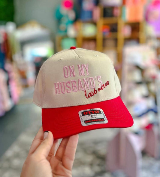 Beige and red cap with text held in front of a blurred store background